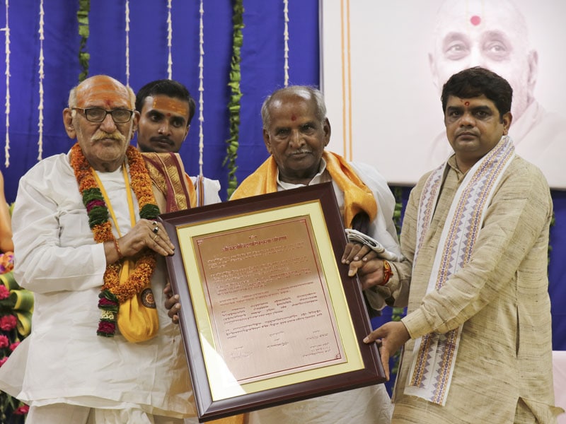 Distinguished Pandits of Shri Kāśī Vidvat Pariṣad present the copper-plated letter of declaration to Mahāmahopādyāya Sadhu Bhadreshdas Swami